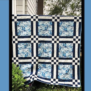 Op de afbeelding: Een blauw-wit quilt met een rasterpatroon. De quilt heeft een herhalend patroon van blauwe en witte vierkanten, met een centraal ontwerp van blauwe en witte afbeeldingen. Het woord "Willow" staat bovenaan.