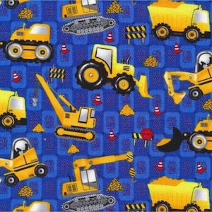 Peut inclure: Tissu bleu avec un motif répété de véhicules de chantier jaunes, tels que des camions et des tracteurs. Le motif comprend également des cônes de signalisation, des panneaux routiers et des tas de sable.