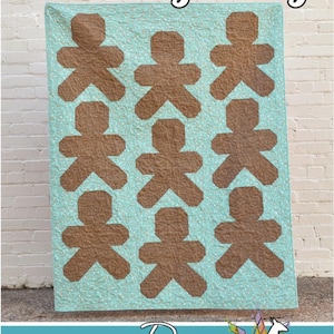 Puede incluir: Un edredón con un patrón repetido de formas de hombre de jengibre marrón sobre un fondo azul claro. Las palabras "Baking Day" están en la parte superior. El logotipo de Running Doe Quilts está en la parte inferior.