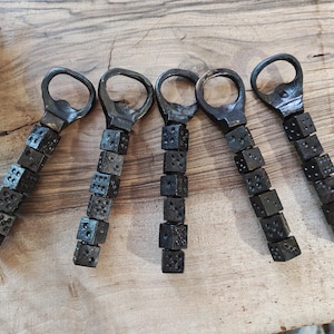 May include: Five black metal bottle openers with a chain of dice attached. Each opener has a different number of dice.