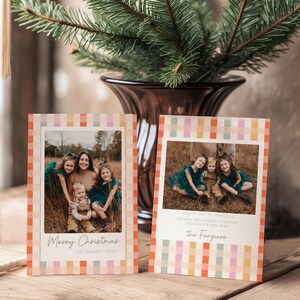 May include: Two holiday greeting cards with family photos, featuring a colorful plaid border. The cards have the text "Merry Christmas" and "We wish you a Merry Christmas and a Happy New Year". A vase with evergreen branches is in the background.