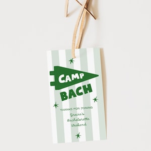 Op de afbeelding: Een rechthoekig label met een groen wimpelontwerp met de tekst "CAMP BACH" in witte letters. Het label heeft een gestreepte achtergrond in lichtgroen en wit, met de tekst "THANKS FOR JOINING Gracie's Bachelorette Weekend". Een leren riem is bevestigd.