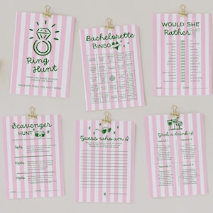 May include: A collection of pink and white striped party game cards, each held by a gold clip. The games include "Ring Hunt", "Bachelorette Bingo", "Would She Rather", "Scavenger Hunt", "Guess Who Am I", and "Grab a Drink If".