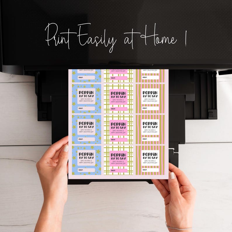 May include: A sheet of printed Valentine's Day gift tags with the text "POPPIN BY TO SAY" in a variety of colors and patterns, including blue, pink, and plaid. The text "Print Easily at Home!" is written in cursive at the top.
