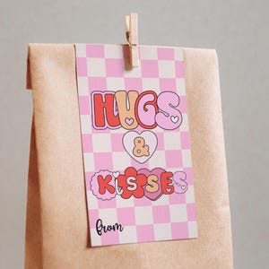 May include: A pink and white checkered gift tag with the text "Hugs & Kisses from" in a retro font. The text is in pink, red, and orange with hearts and flowers.