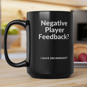 May include: Black coffee mug with white text that reads "Negative Player Feedback? I Have DM Immunity".
