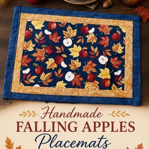 May include: A rectangular fabric placemat featuring a dark blue center panel with a pattern of red apples and multicolored autumn leaves. The center is framed by a mustard yellow border with a thin white line pattern and a solid dark blue outer edge.