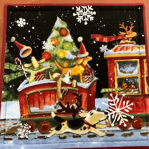 May include: A square Christmas-themed coaster featuring a whimsical illustration. The design includes dogs, a Christmas tree, a train, and snowflakes against a black background. The coaster has a red border and is likely made of absorbent material.