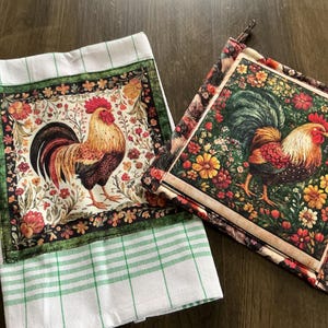 Pode incluir: Um pano de cozinha xadrez branco e verde e um pegador de panela quadrado. Ambos apresentam um design de galo colorido com uma borda floral. O galo tem penas vermelhas, douradas e pretas. O pegador de panela tem um fundo floral.