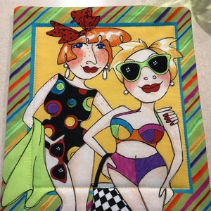 May include: Two cartoon women in colorful swimsuits and sunglasses. The woman on the left is wearing a black swimsuit with white polka dots and a green towel. The woman on the right is wearing a multi-colored swimsuit and a black and white checkered bag.