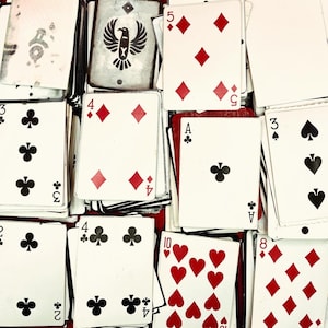 Puede incluir: Un conjunto de naipes, con diferentes palos y números. Las cartas son blancas con símbolos de diamantes rojos y tréboles negros. Algunas cartas muestran los números 2, 3, 4, 5, 8 y 10. Una carta tiene un diseño de águila.