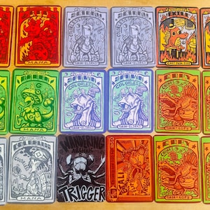 May include: A collection of colorful trading cards with various illustrations and text. The cards feature images of creatures, symbols, and text such as "Mana", "Colorless", and "Trigger". The cards are in shades of red, green, blue, and orange.