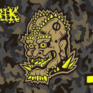 May include: A graphic design featuring a stylized, angry face with yellow accents and a camouflage background. The word "KRRIK" is in yellow, stylized text. A Carhartt logo is in the upper right corner.