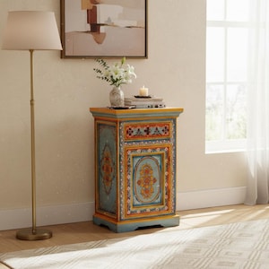 May include: A rectangular wooden cabinet featuring a light blue base color with hand-painted floral motifs in orange, yellow, and white. The cabinet includes one top drawer and a single door with decorative borders in yellow and orange tones.
