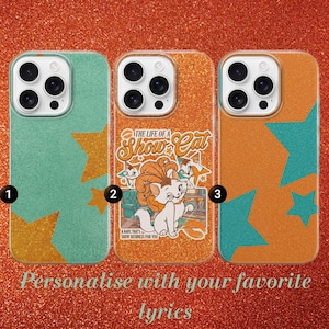 May include: Three glittery phone cases. One is teal with gold stars, the second is orange with a cat graphic and text "The Life of a Show Cat", and the third is orange with teal stars. The text "Personalise with your favorite lyrics" is at the bottom.