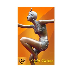 May include: Bronze sculpture of a woman in a stylized bathing suit, with a feathered headdress, posed in a dynamic dance-like position. The sculpture has a light patina finish. The text "QB Light Patina" is visible in the lower right corner.