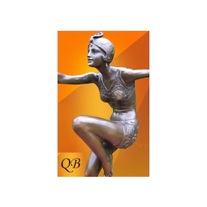 May include: Bronze sculpture of a woman in a swimsuit, with her arm outstretched and her leg bent, against an orange background. The sculpture is labelled "QB".