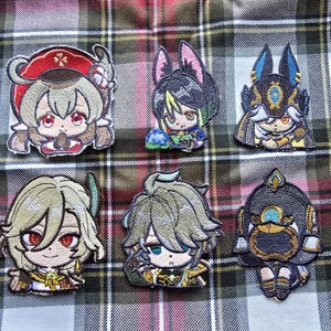 May include: Six embroidered patches featuring anime characters. The patches are colorful and feature various designs, including a girl with red hair, a girl with blue hair, a girl with green hair, a girl with purple hair, a girl with pink hair, and a girl with yellow hair.