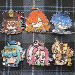 Puede incluir: Parches bordados con personajes de estilo anime con colores vibrantes. Los parches muestran diseños detallados con varios peinados y atuendos. Los parches están sobre un fondo a cuadros.