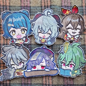 May include: Six embroidered patches featuring anime characters with different colored hair and clothing. The patches are all in a cartoon style and have a variety of expressions.