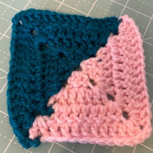 May include: A crocheted square with a teal and pink color scheme. The square is made with a simple stitch pattern and has a diagonal line where the colors change.