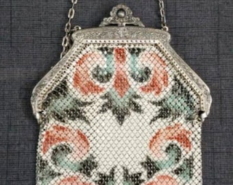 May include: A silver mesh purse with a floral pattern in shades of pink, green, and white. The purse has a silver chain strap and a fringe detail.