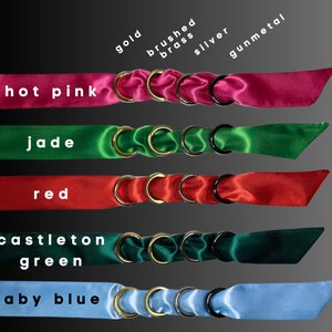 Puede incluir: Cinco tiras de cinta de sat&eacute;n en diferentes colores, cada una con cuatro anillos unidos. Los colores son rosa intenso, jade, rojo, verde castleton y azul beb&eacute;. Los anillos son de oro, lat&oacute;n cepillado, plata y metal gris.