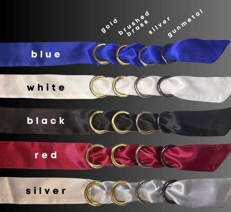 Puede incluir: Cinco cintas de sat&eacute;n de diferentes colores, azul, blanco, negro, rojo y plateado, con anillos de oro, lat&oacute;n cepillado, plata y metal gris unidos a cada cinta.