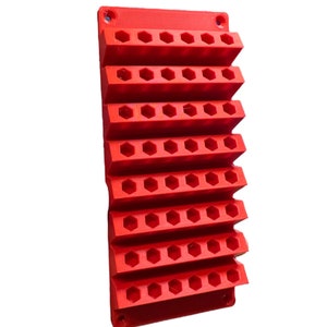 May include: Red plastic wall-mounted organizer with hexagonal slots for holding tools or other small items.