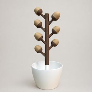 May include: A brown and tan decorative tree-shaped object with acorn-like buds, labeled with the days of the week. The tree is set in a white ceramic pot. The design is minimalist and modern.