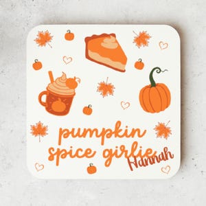 May include: A square, off-white coaster with autumn illustrations. It features a pumpkin spice latte, pumpkin pie, pumpkins, and falling leaves. The text "pumpkin spice girlie" and the name "Hannah" are also included.