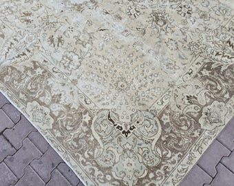 May include: A vintage beige rug with an intricate floral pattern and a border of scrolling designs in shades of brown and cream. The rug's central field features a repeating pattern of small circles.