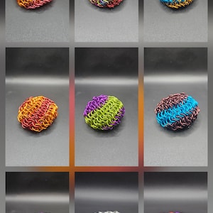 Puede incluir: Una cuadrícula de nueve estropajos de cota de malla en varios colores. Los estropajos redondos están hechos de anillos de metal entrelazados. Los colores incluyen rojo, naranja, amarillo, azul, verde, morado y plateado.