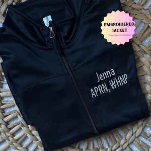 May include: Black embroidered jacket with the text "EMBROIDERED JACKET - The Oaks On Ontario" and "Jenna APRN, WHNP" in white thread.