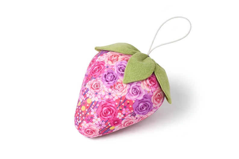 Single pink fabric strawberry ornament with lace bow isolated on white background
