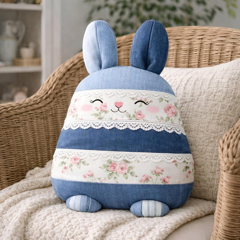 Blue bunny pillow with lace stripes placed on a wicker chair.