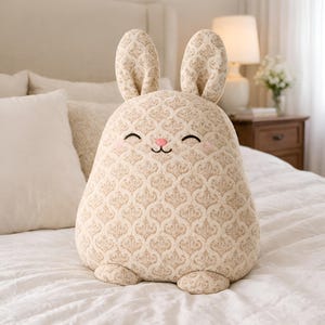Neutral beige bunny pillow in textured fabric in a cozy bedroom setting.
