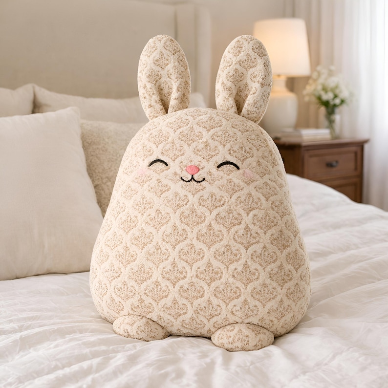 Neutral beige bunny pillow in textured fabric in a cozy bedroom setting.