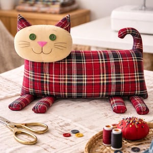 Red plaid cat pillow on table with scissors and threads, sewing process, DIY cat pillow pattern tutorial