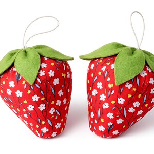 Pair of small red plush strawberries with hanging loops and lace bows isolated on white