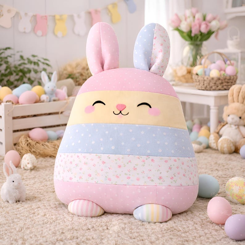 Pink bunny pillow with soft striped body and pastel Easter decorative details.