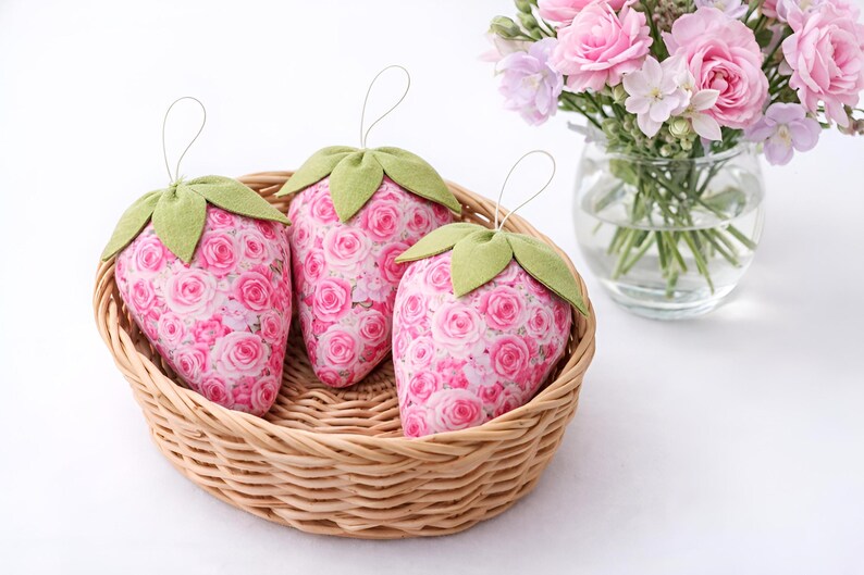 Wicker basket filled with pink strawberry ornaments with lace bows styled with flowers on table
