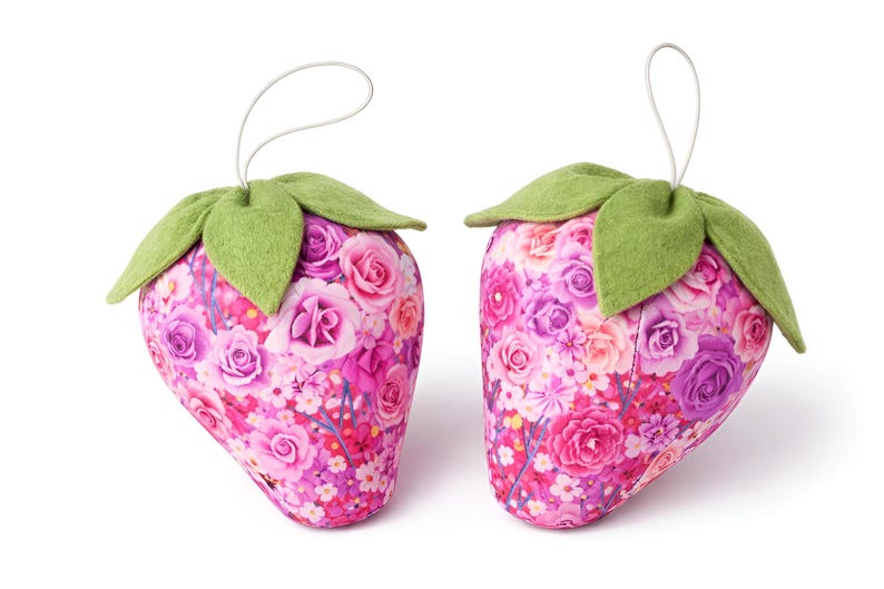 Two pink fabric strawberry ornaments with green felt leaves and lace bows isolated on white