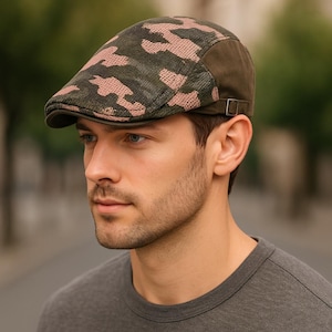 Puede incluir: Gorra plana con estampado de camuflaje verde y rosa, con visera y panel lateral marrón oscuro. La gorra tiene una pequeña correa ajustable en el lateral. La gorra está hecha de tela texturizada.