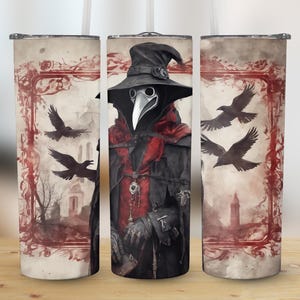 May include: Three stainless steel tumblers with a gothic design. The center tumbler features a black-clad figure wearing a plague doctor mask and hat. The other two tumblers feature a red and white floral design with ravens.