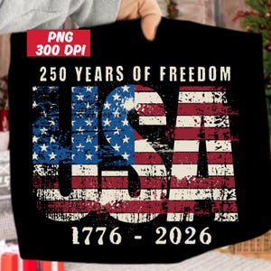 May include: Black t-shirt featuring a distressed USA flag design. The flag incorporates red and white stripes and a blue field with white stars. The text "250 YEARS OF FREEDOM" and "1776 - 2026" are printed above and below the flag.