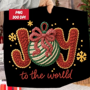 May include: Black Christmas-themed design with the word "JOY" in red knitted letters, a green and white striped ornament, and the phrase "to the world" in red script. Gold snowflakes and dots complete the design.