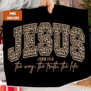 May include: Black fabric featuring the word "JESUS" in large, leopard print letters with gold glitter edging. Underneath, the text "JOHN 14:6" and "The way, the truth, the life" are written in a cursive font. The image includes a "PNG 300 DPI" label.