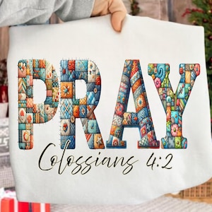 May include: White fabric with the word "PRAY" in colorful patchwork letters. Below, the text "Colossians 4:2" is written in cursive. The letters are filled with various patterns and colors, including blue, orange, and green, giving it a handcrafted look.