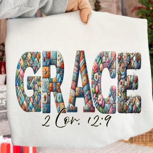 Peut inclure: Une couverture blanche avec le mot "GRACE" en grandes lettres colorées de style patchwork. En dessous, le texte "2 Cor. 12:9" est écrit en noir. Les lettres sont remplies de motifs et de couleurs variés.